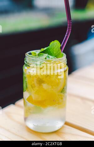 Cocktail de limonade garni de citron et de menthe sur la table. Boisson non alcoolisée dans un pot en verre maçon vintage. Boisson au citron dans un verre Banque D'Images