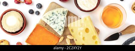 Assiette de fromages flatlay panorama sur un fond blanc. Fromage bleu, rouge, fromage de chèvre, et d'autres, avec du vin, des fruits et d'amandes Banque D'Images