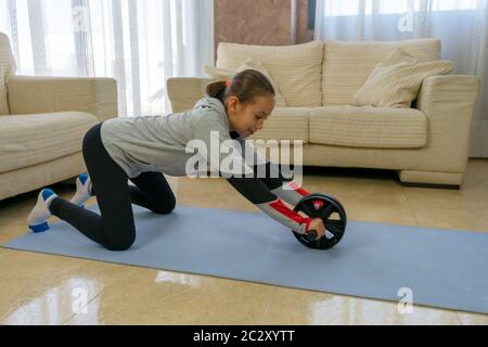 Petite fille faisant du sport dans le salon à la maison sur un tapis bleu Banque D'Images