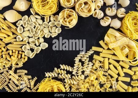 Design italien des pâtes avec espace de copie, une couche plate d'une variété de types de pâtes, prises de dessus sur un fond noir avec un lieu Banque D'Images