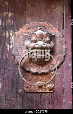 Image d'un ancien porte-clé en métal stylisé à tête de lion sur une porte. Ancienne ville de Zhou Cun, ville de Jinan, province de Shandong; Chine. Orientation verticale Banque D'Images