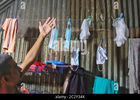 Dhaka, Bangladesh. 18 juin 2020. Un homme qui pendait des masques et des gants de main sur une corde après les avoir lavées pour être utilisé à nouveau pendant la pandémie du coronavirus à Korail slum.la plus grande taupe de la capitale Dhaka, Korail compte près de cinquante mille habitants qui ne connaissent pas la maladie mortelle. Les bidonvilles présentent un grand risque pour la santé de résultats extrêmes, car les endroits bondés sont très sensibles à l'épidémie de Covid-19. Crédit: Sultan Mahmud Mukut/SOPA Images/ZUMA Wire/Alay Live News Banque D'Images