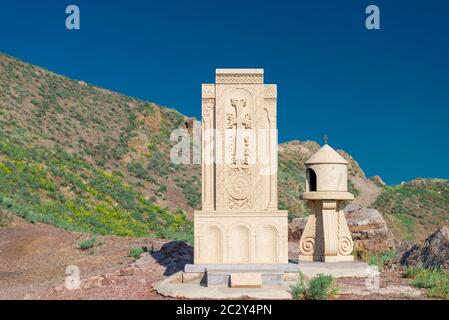 Par temps ensoleillé, un khachkar sculpté en Arménie sur fond de montagne Banque D'Images