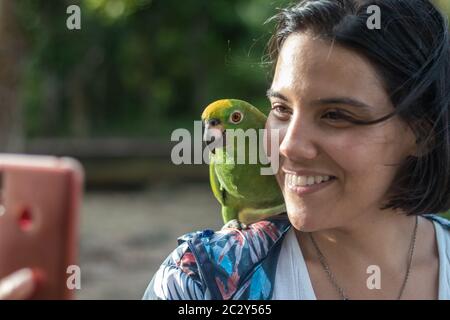Femme interprète un selfie avec un perroquet dans la jungle du delta de l'Orinoco au Venezuela Banque D'Images