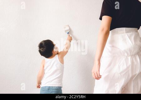 Petit enfant avec maman peignant le mur avec une brosse. Mère et fils. Banque D'Images