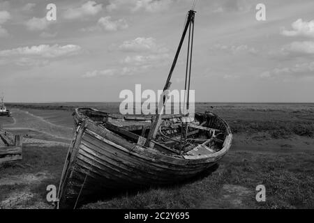 Vieux voilier en bois a été délaché sur la côte nord du Norfolk au Royaume-Uni avec une étendue de côte et de ciel ouverts en noir et blanc Banque D'Images