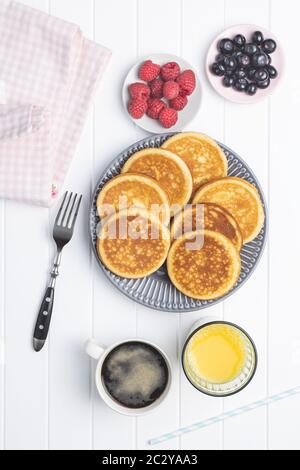 Crêpes maison douces avec bleuets et framboises. Délicieux petit déjeuner avec café et jus de fruits. Vue de dessus. Banque D'Images