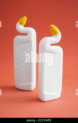 deux flacons en plastique blanc sans étiquette avec produits de nettoyage sur fond rose, gel toilette, deux flacons avec bouchons de distribution jaunes. Banque D'Images