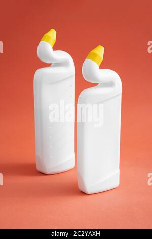 deux flacons en plastique blanc sans étiquette avec produits de nettoyage sur fond rose, gel toilette, deux flacons avec bouchons de distribution jaunes. Banque D'Images