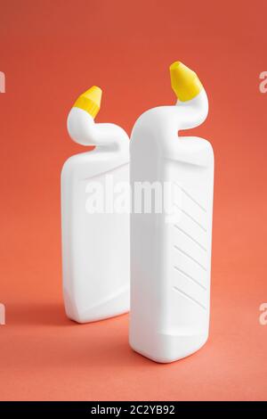 deux flacons en plastique blanc sans étiquette avec produits de nettoyage sur fond rose, gel toilette, deux flacons avec bouchons de distribution jaunes. Banque D'Images