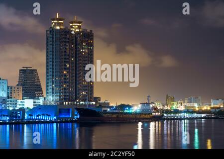 Les lumières de la ville et l'horizon de la ville moderne taïwanaise Kaohsiung se reflétant dans l'eau la nuit Banque D'Images