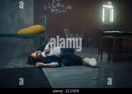 Une femme victime d'un kidnappeur de maniaque dormant sur le sol menotté au lit. L'enlèvement est un crime grave, l'horreur d'enlèvement, la violence Banque D'Images