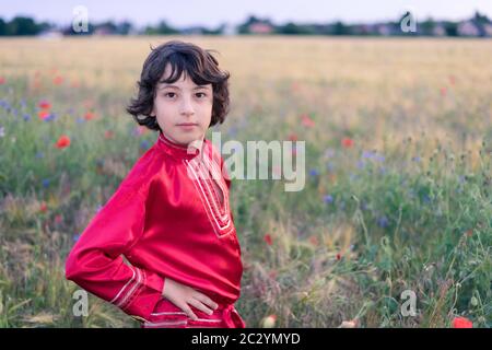 Portrait d'un garçon dans un champ avec des fleurs sauvages. Un garçon vêtu d'une chemise paysanne russe. Banque D'Images