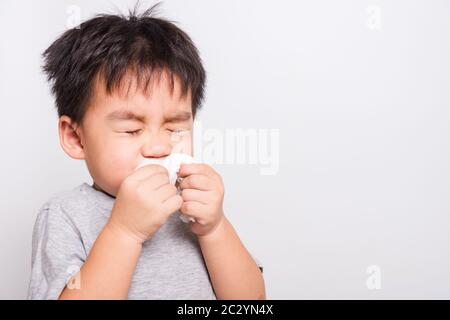 Gros plan visage asiatique, Petits enfants garçon nettoyage nez avec tissu sur fond blanc avec espace de copie, soins médicaux de santé Banque D'Images