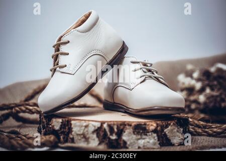 Image vintage des chaussures pour enfants. Chaussures en cuir blanc pour enfants sur fond de bois rustique ancien. Banque D'Images