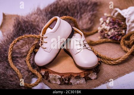 Image vintage des chaussures pour enfants. Chaussures en cuir blanc pour enfants sur fond de bois rustique ancien. Banque D'Images