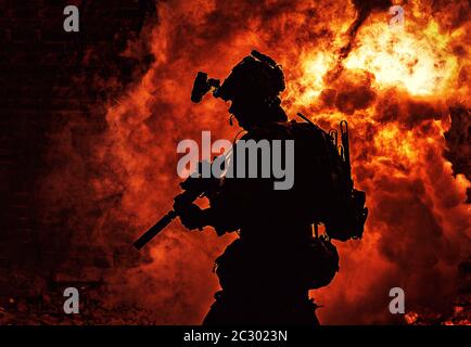 Silhouette de soldat d'infanterie moderne, combattant d'élite de l'armée en munitions tactiques et casque, debout avec une carabine de service d'assaut dans les mains sur backgroun Banque D'Images