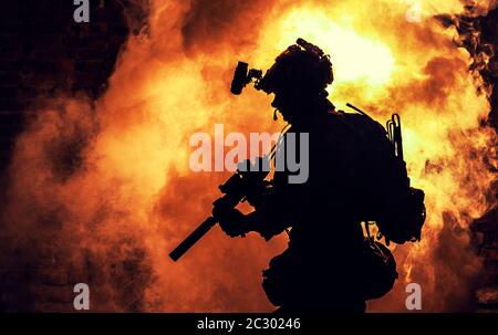 Silhouette de soldat d'infanterie moderne, combattant d'élite de l'armée en munitions tactiques et casque, debout avec une carabine de service d'assaut dans les mains sur backgroun Banque D'Images