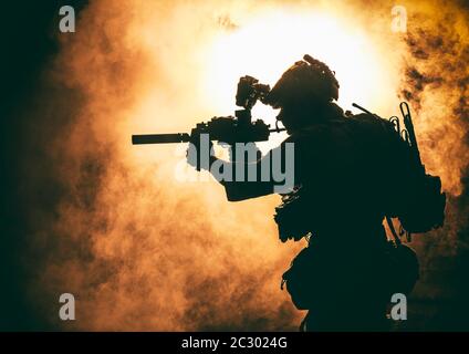 Silhouette de soldat d'infanterie moderne, combattant d'élite de l'armée en munitions tactiques et casque, debout avec une carabine de service d'assaut dans les mains sur backgroun Banque D'Images