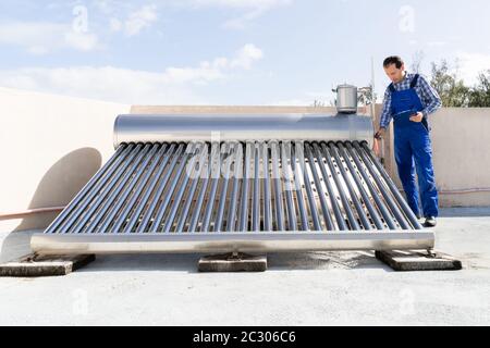 Plombier Mâle Faisant L'Inspection De La Chaudière À Énergie Solaire Banque D'Images