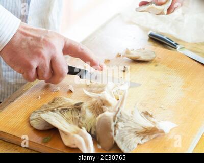 Homme âgé coupant des champignons sur planche en bois Banque D'Images