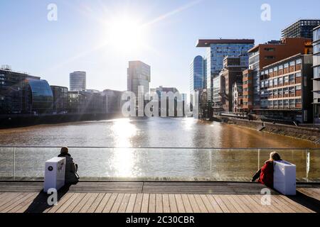 Femmes assises sous le soleil d'hiver sur la jetée en bois de Medienhafen, Düsseldorf, Rhénanie-du-Nord-Westphalie, Allemagne Banque D'Images