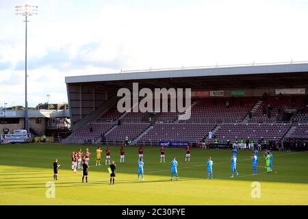 Les équipes et les officiels se mettent en file d'attente autour du cercle central pour un moment de applaudissements afin de rendre hommage aux efforts du NHS et des travailleurs clés pendant le confinement du coronavirus lors du match de demi-finale de la première jambe de la Sky Bet League 2 au PTS Academy Stadium, à Northampton. Banque D'Images