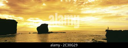 Randonneur admirant la silhouette de Sweetheart Rock au coucher du soleil jaune moody, Hawaii, États-Unis Banque D'Images