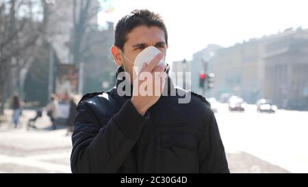 COVID-19 Homme dans la rue de ville portant un masque de protection pour la propagation de la maladie de Coronavirus 2019. Portrait de l'homme avec masque chirurgical sur le visage contre Banque D'Images