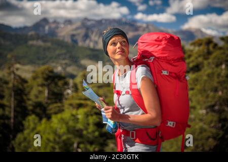 Joli randonneur féminin en haute montagne à l'aide d'une carte pour trouver un chemin à travers une chaîne de montagne Banque D'Images