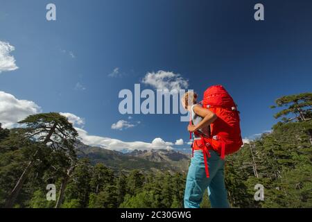 Jolie, female hiker dans des montagnes de son sac à dos d'emballage Banque D'Images