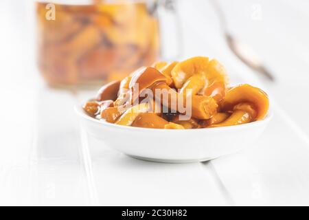 Champignons marinés. Champignons marinés dans un bol sur une table blanche. Banque D'Images