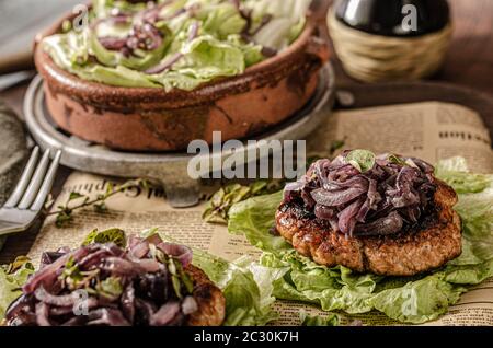 Délicieux bifteck avec oignon rouge caramélisé et herbes fraîches sur la salade Banque D'Images