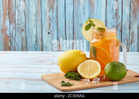 Limonade aux agrumes avec glace, feuilles de menthe, citron et rondelles de lime sur table en bois bleu. Limonade maison avec des citronnades. Boisson fraîche saine Banque D'Images