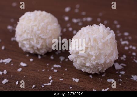 Gros plan de pralines de noix de coco au chocolat blanc sur du bois brun texture Banque D'Images