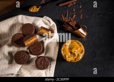 biscuits alfajores avec crème dulce de leche sur pierre noire, macarons couverts de chocolat vue de dessus Banque D'Images