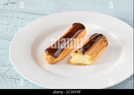 Éclairs avec garniture au chocolat sur la plaque de service Banque D'Images