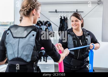 Femme moulante et bosse ayant un entraînement ems ensemble dans une salle de gym Banque D'Images