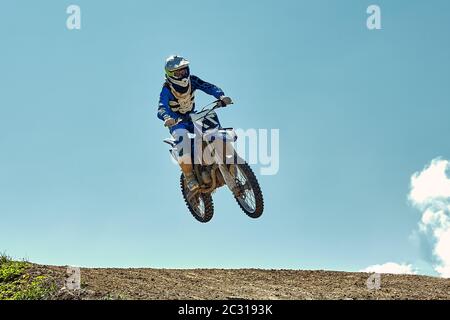 Concept extrême, défiez-vous. Saut extrême sur une moto sur un fond de ciel bleu avec des nuages. Copier l'espace, tout ou rien. Banque D'Images