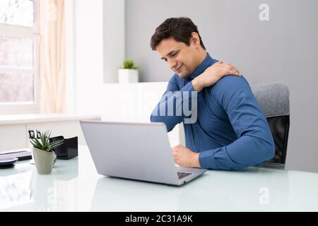 Homme d'âge mûr souffrant de douleur à l'épaule sur le lieu de travail Banque D'Images