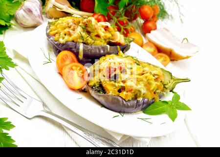 De poitrine fumé avec des aubergines farcies, tomates, oignons, carottes à l'ail, le fromage et les herbes dans une assiette sur un essuie-tout sur planche de bois backgroun Banque D'Images