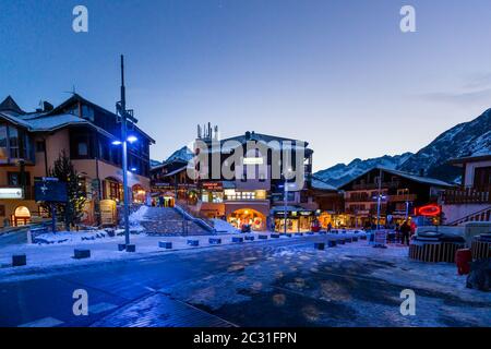 Vie nocturne dans un village alpin avec maisons traditionnelles en bois, boutiques et restaurants Banque D'Images