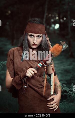 Magnifique huntress indien dans les bois. Poser avec le tomahawk Banque D'Images