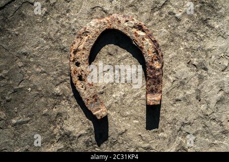 Old weathered fer rouillé sur fond de pierre gros plan en fer à cheval Banque D'Images