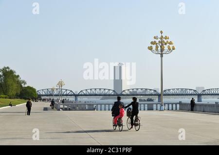 Pyongyang, Corée du Nord - 1 mai 2019: Scène de rue UNE jeune famille, un homme, une femme et un enfant se balade le long du remblai près de la tour de Juche sur deux bi Banque D'Images