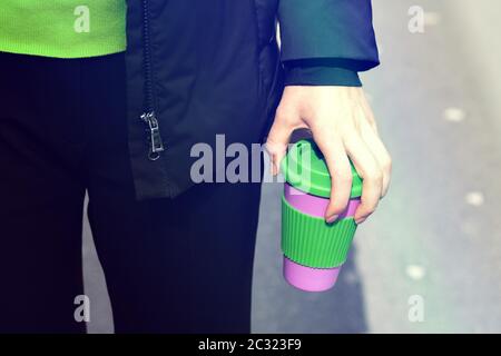 Les mains des femmes tiennent le mug à café réutilisable à l'extérieur. Emportez votre café partout avec votre tasse de voyage réutilisable. Aucun gaspillage. Concept de mode de vie durable. Banque D'Images