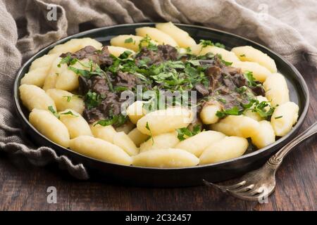 Boulettes de pommes de terre traditionnelles polonaises fraîchement cuites, servies avec une sauce aux champignons et du persil frais Banque D'Images