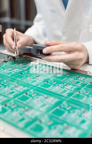 Technicien insérant des composants électroniques dans un boîtier de distribution électrique pour l'assemblage d'un produit électronique Banque D'Images