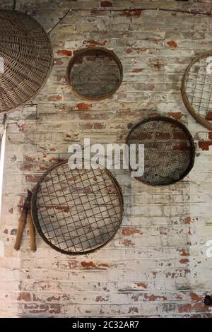 Quatre grilles de jardinage en métal vintage ou devinettes accrochée à un mur de brique rouge blanc avec des loppers et un panier en osier. Banque D'Images