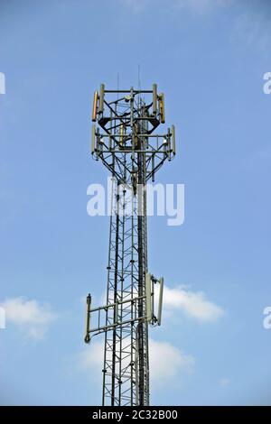 Mât de télécommunications avec différentes antennes pour téléphones mobiles. Fond de ciel bleu avec quelques nuages blancs. Banque D'Images